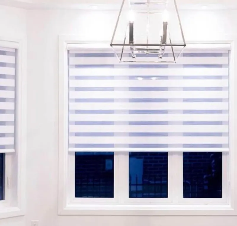 A wide white zebra blind under a dining-room chandelier