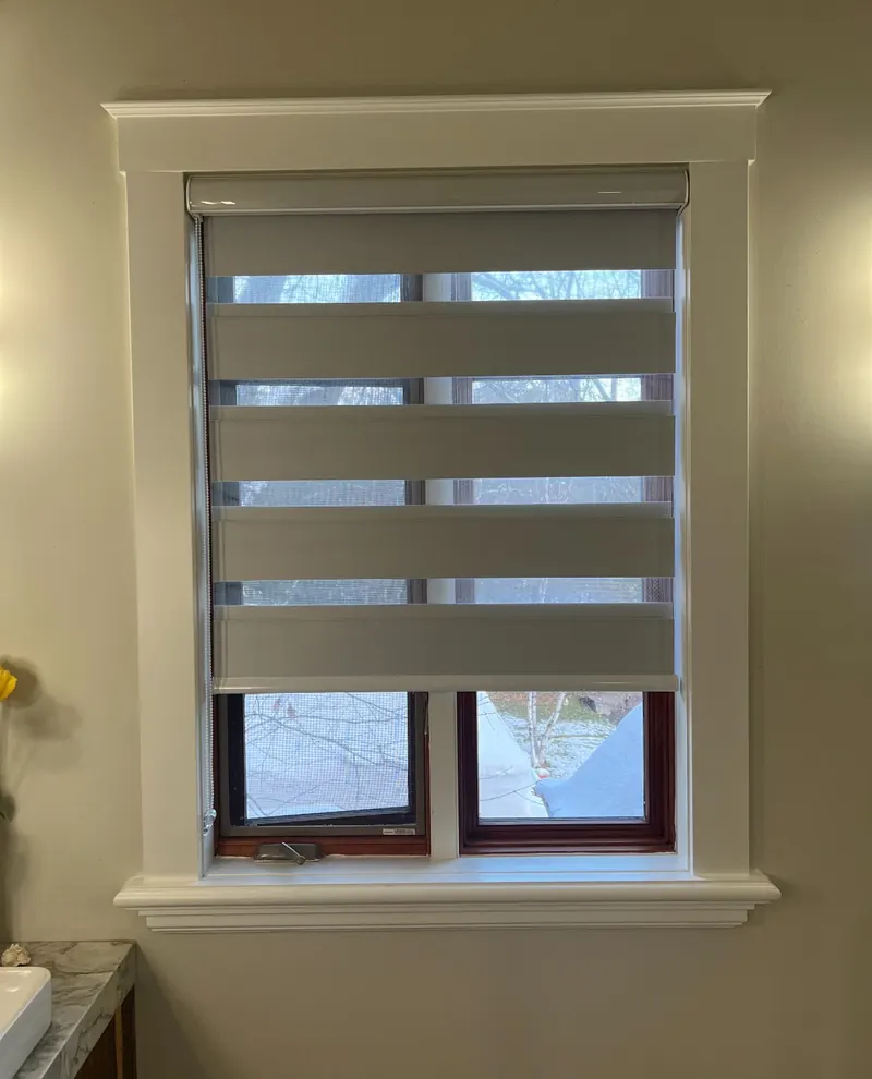 A grey zebra blind on a wood-trimmed window