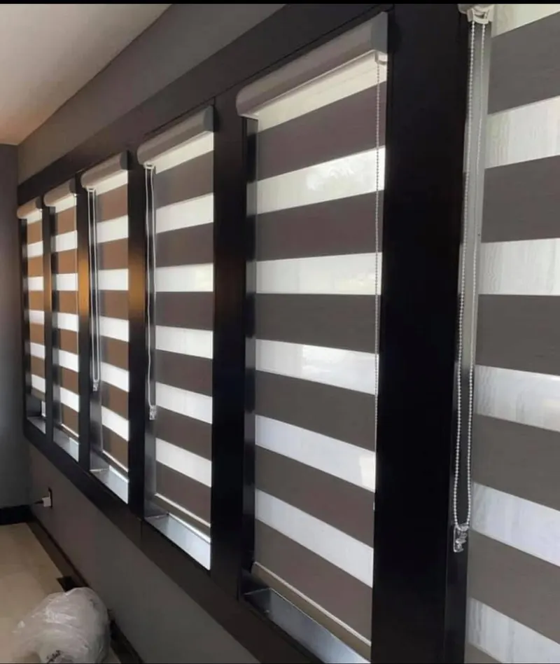 A row of charcoal zebra blinds across a wall of windows
